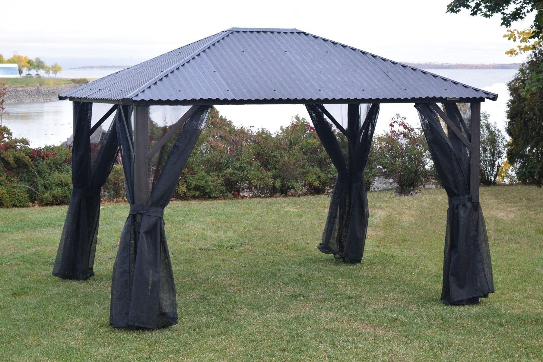Gazebo Corriveau avec moustiquaire noire retenue à chaque poteau dans une cour québécoise en automne