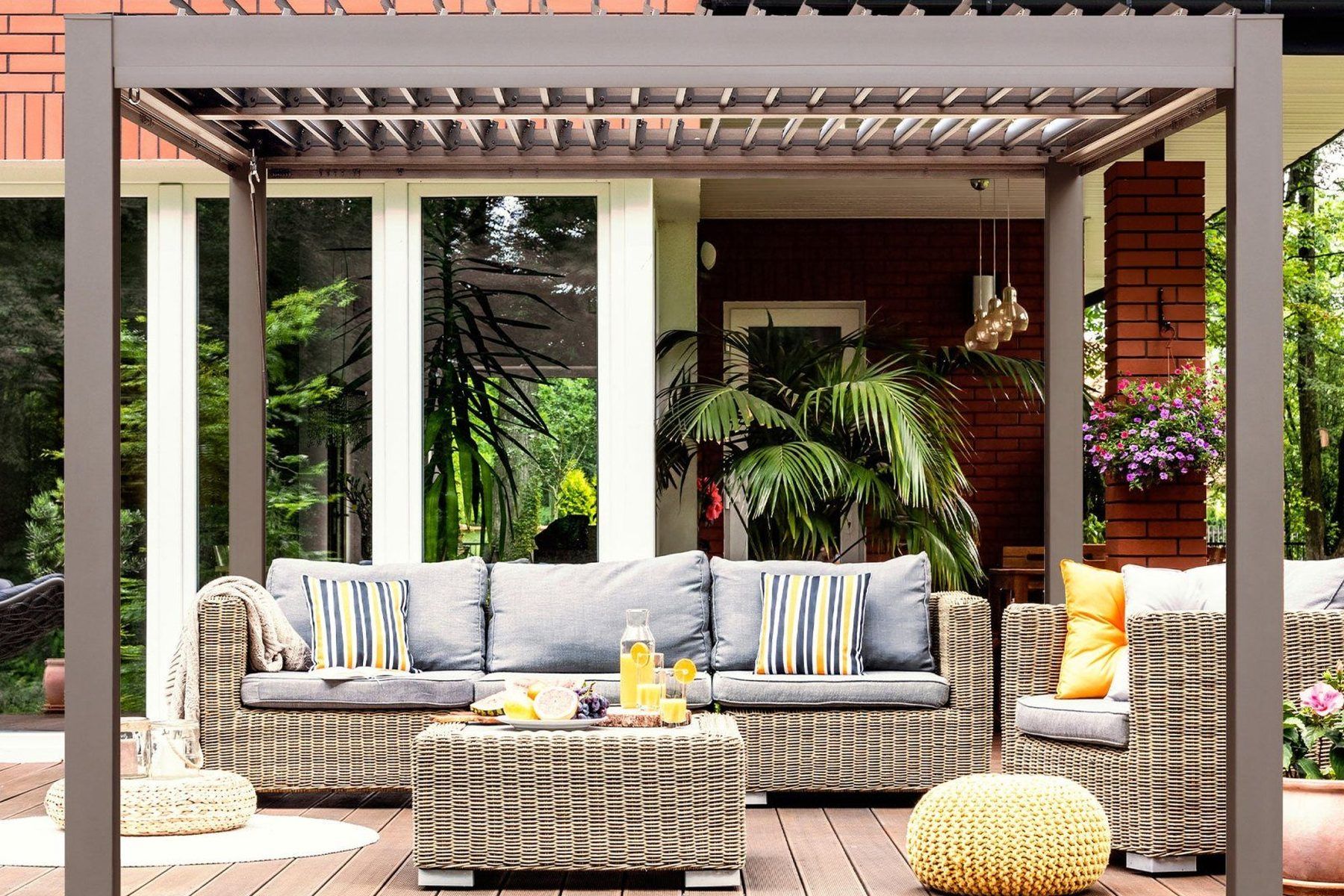 Greige Gazebo Penguin Vikos louvered aluminum pergola over a deck lounge set beside a brick house