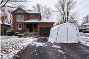 Winter car shelter on a snowy Canadian driveway beside a brick house