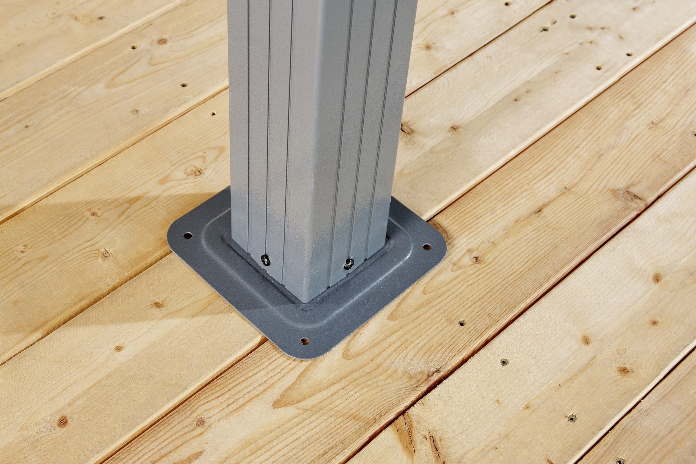 Plaque de base d'un poteau de gazebo Sojag sur une terrasse en bois, prête à être vissée